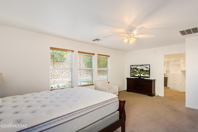 bedroom with a spacious closet, ceiling fan, a closet, and light colored carpet