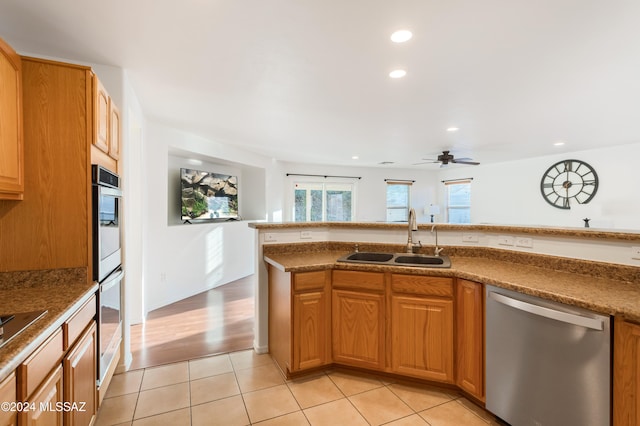 kitchen featuring ceiling fan, appliances with stainless steel finishes, sink, and light wood-type flooring