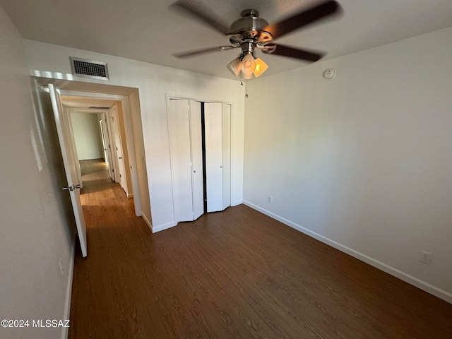 unfurnished bedroom with a closet, dark wood-type flooring, and ceiling fan