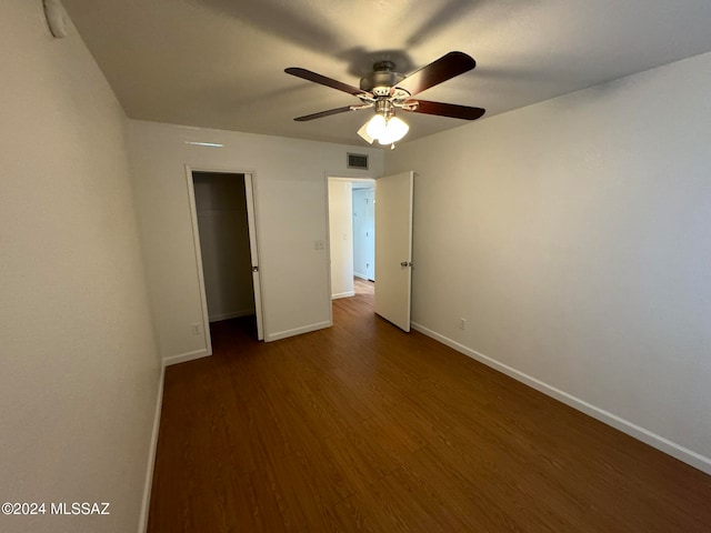 unfurnished bedroom featuring dark wood-type flooring, a closet, and ceiling fan