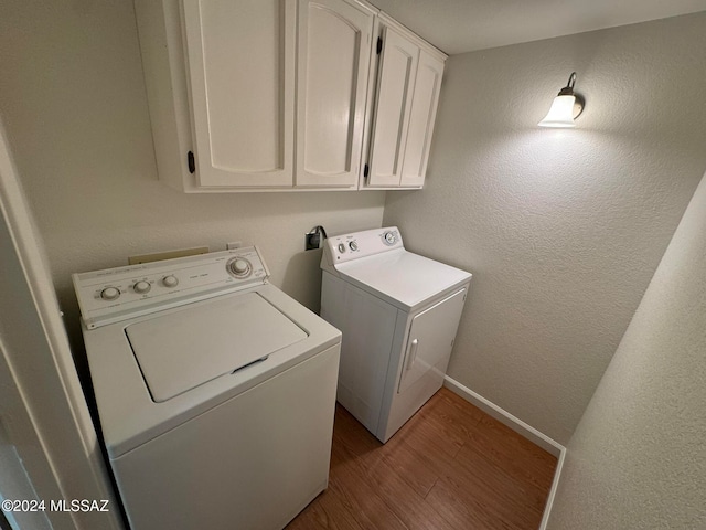 washroom with light hardwood / wood-style floors, cabinets, and separate washer and dryer