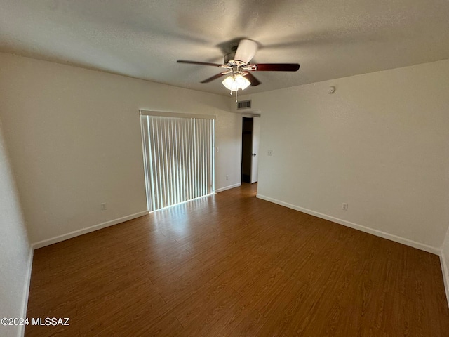 spare room with dark wood-type flooring, a textured ceiling, and ceiling fan