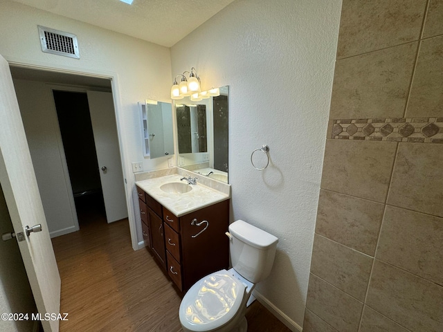 bathroom with vanity, hardwood / wood-style floors, toilet, and a textured ceiling