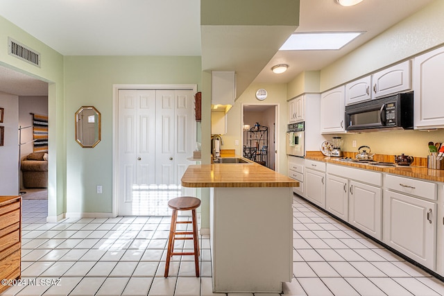 kitchen featuring stainless steel appliances, white cabinetry, a center island with sink, and sink