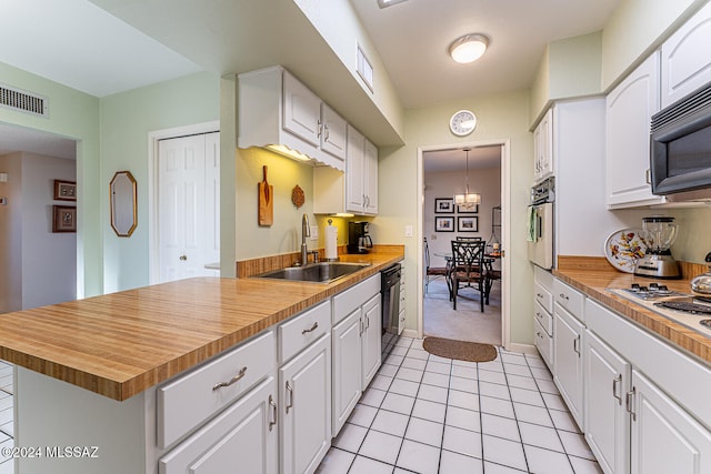 kitchen with black appliances, sink, a chandelier, white cabinetry, and light tile patterned flooring