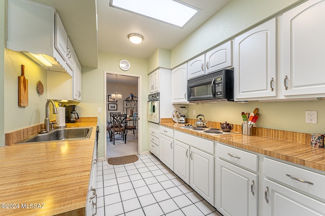 kitchen featuring sink, light tile patterned floors, white gas stovetop, oven, and white cabinets