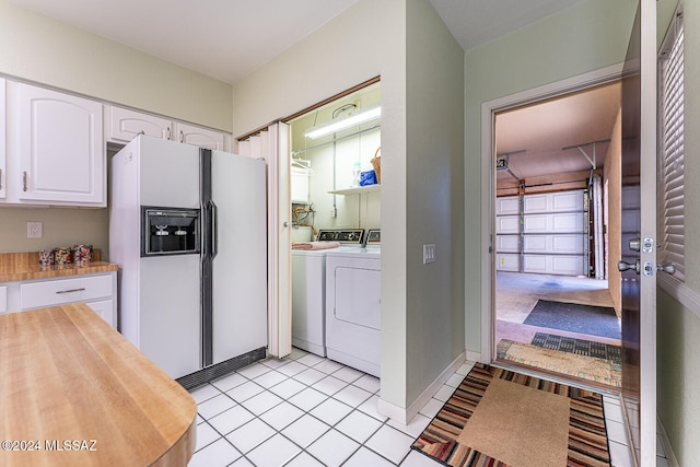 kitchen with white cabinets, washing machine and dryer, white refrigerator with ice dispenser, and light tile patterned floors