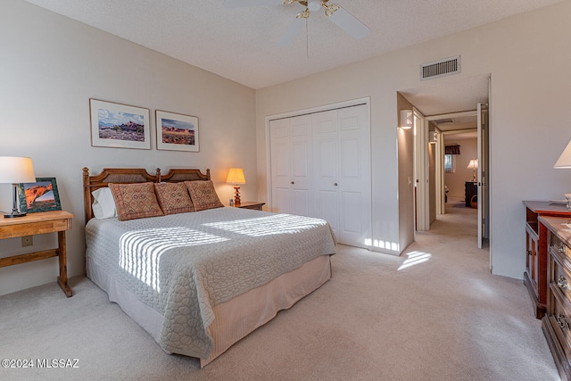 carpeted bedroom with ceiling fan, a textured ceiling, and a closet