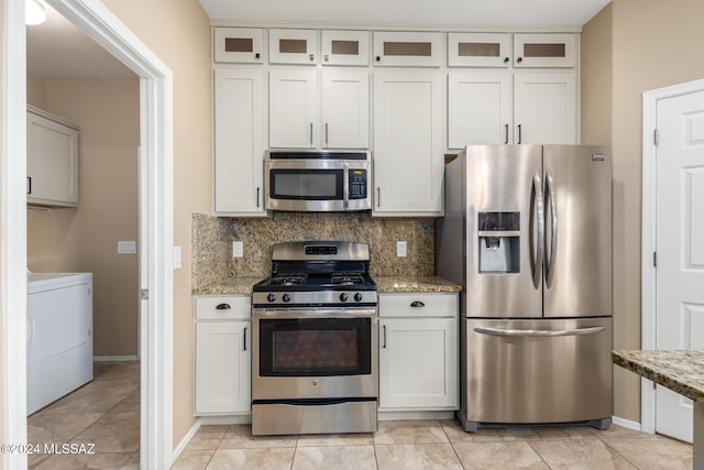 kitchen with washer / dryer, appliances with stainless steel finishes, white cabinets, light stone countertops, and backsplash