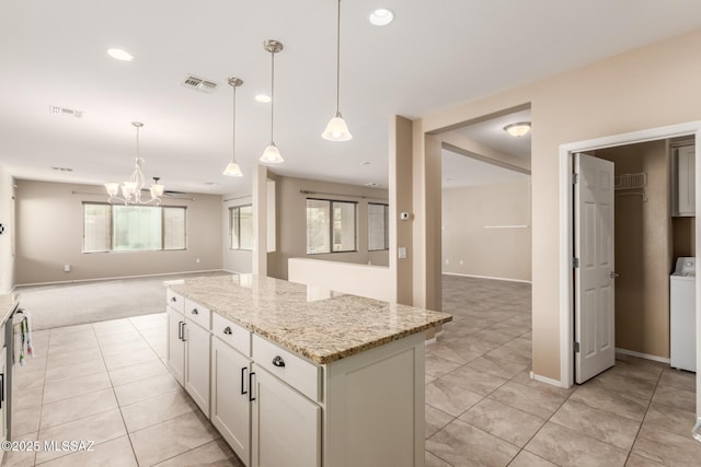 kitchen featuring decorative light fixtures, a center island, light stone countertops, and a wealth of natural light