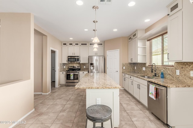 kitchen featuring appliances with stainless steel finishes, sink, white cabinets, hanging light fixtures, and a center island