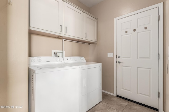 laundry area with washing machine and dryer, cabinets, and light tile patterned flooring