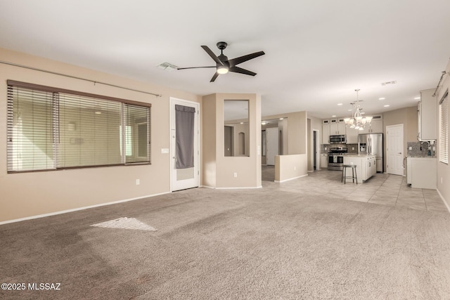 unfurnished living room with light colored carpet and ceiling fan with notable chandelier