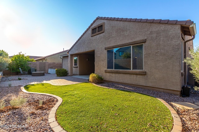 back of house featuring a lawn and a patio area