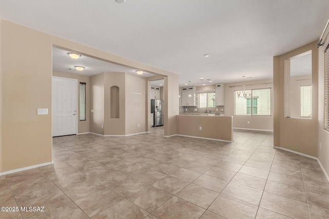 unfurnished living room with an inviting chandelier and light tile patterned floors