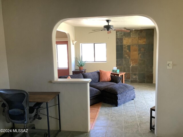 tiled living room with tile walls and ceiling fan