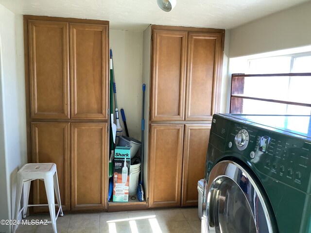 laundry area with washer / dryer, light tile patterned flooring, and cabinets