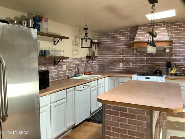 kitchen with sink, white cabinetry, hanging light fixtures, and white appliances