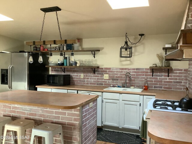 kitchen with sink, decorative light fixtures, white cabinets, a breakfast bar area, and stainless steel refrigerator with ice dispenser