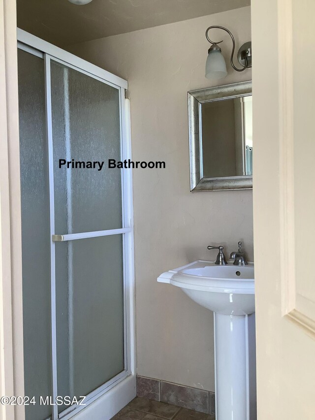 bathroom featuring a shower with door, sink, and tile patterned flooring