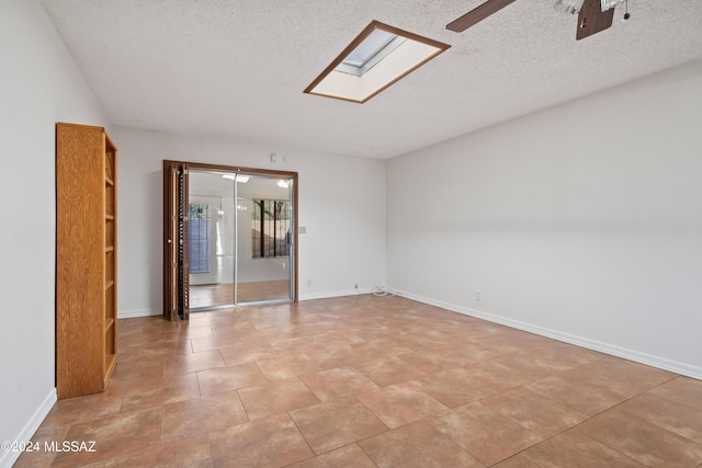 unfurnished room with ceiling fan, a textured ceiling, and a skylight