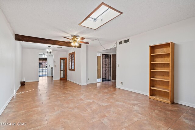 unfurnished room featuring a textured ceiling, beam ceiling, a skylight, and ceiling fan with notable chandelier