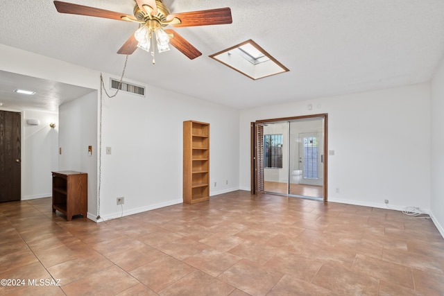 spare room featuring ceiling fan, a skylight, and a textured ceiling