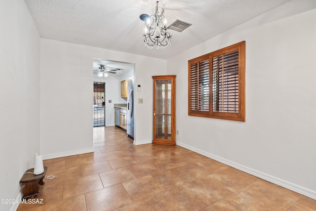 tiled spare room featuring ceiling fan with notable chandelier and a textured ceiling