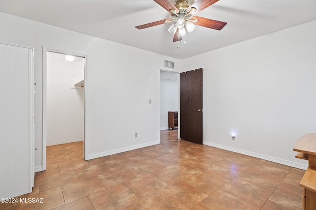 unfurnished bedroom featuring a spacious closet and ceiling fan