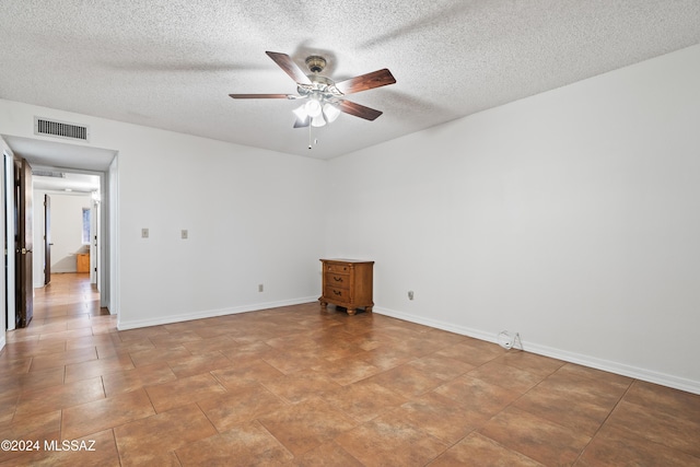 unfurnished room with ceiling fan and a textured ceiling