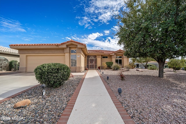 mediterranean / spanish-style home with a garage, driveway, a tile roof, and stucco siding