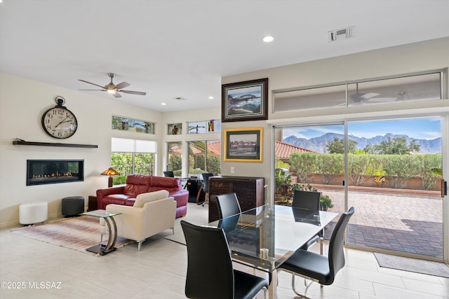 dining room with a mountain view, recessed lighting, a ceiling fan, visible vents, and a glass covered fireplace