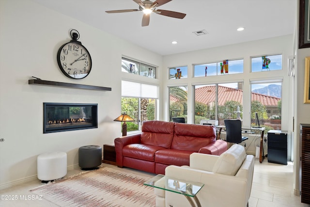 living room with visible vents, baseboards, a ceiling fan, a glass covered fireplace, and recessed lighting