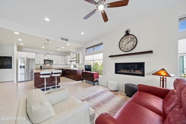 living area featuring baseboards, visible vents, a ceiling fan, and recessed lighting