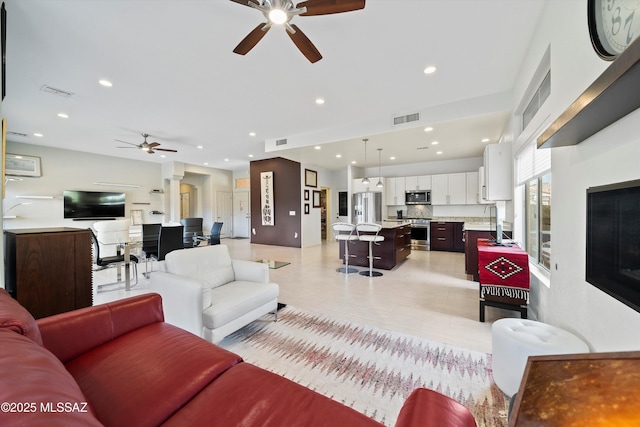 living area featuring a ceiling fan, visible vents, and recessed lighting