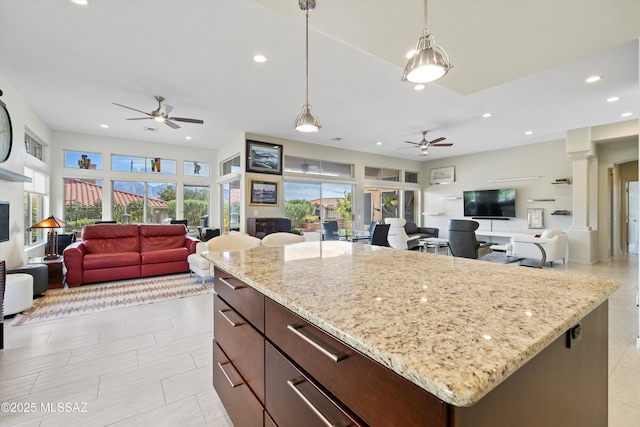 kitchen featuring ceiling fan, recessed lighting, open floor plan, a center island, and decorative light fixtures