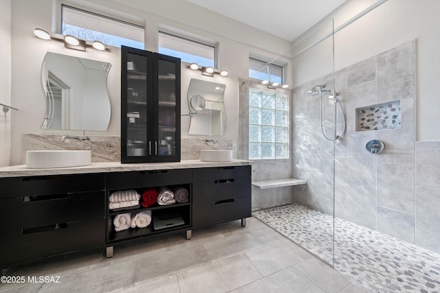 full bath with double vanity, walk in shower, tile patterned flooring, and a sink