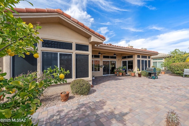 rear view of house with stucco siding, ceiling fan, and a patio