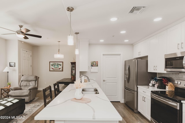 kitchen featuring white cabinets, hanging light fixtures, dark hardwood / wood-style floors, light stone countertops, and appliances with stainless steel finishes