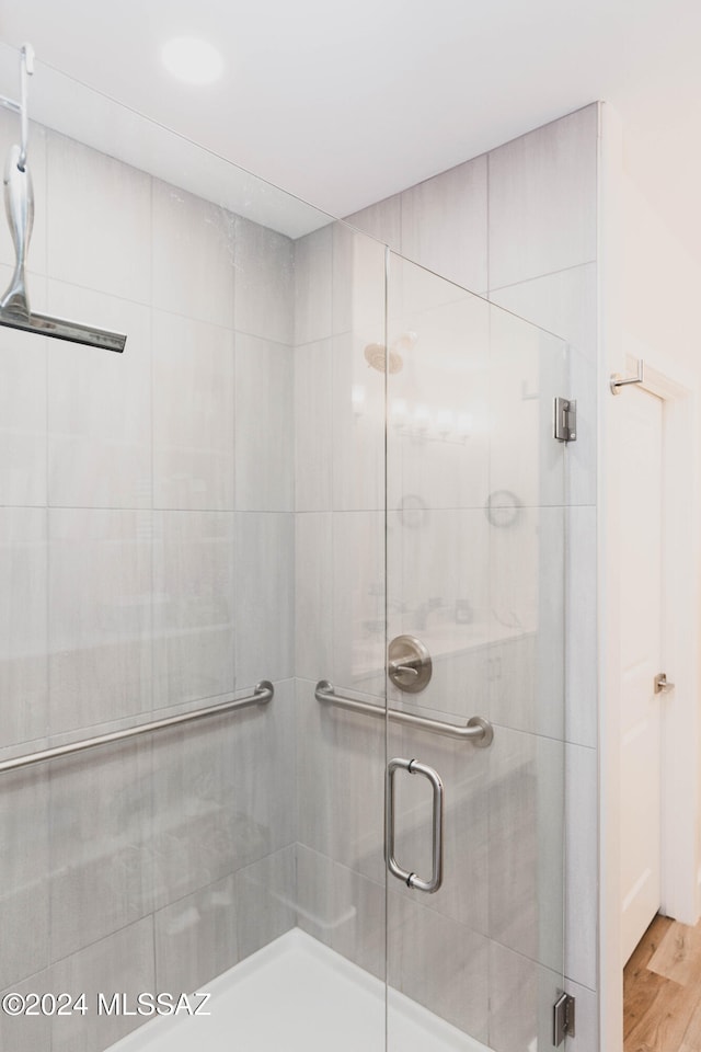 bathroom with hardwood / wood-style floors and a shower with door