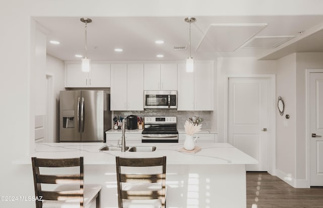 kitchen featuring light stone countertops, stainless steel appliances, sink, decorative light fixtures, and white cabinets