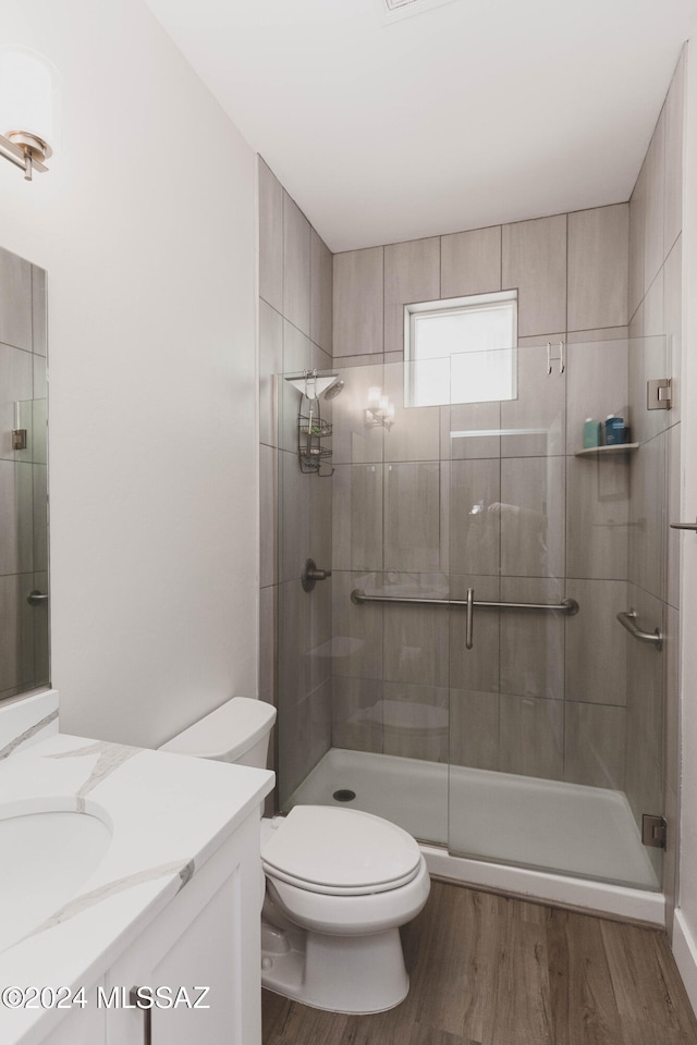 bathroom featuring hardwood / wood-style floors, vanity, toilet, and a shower with door