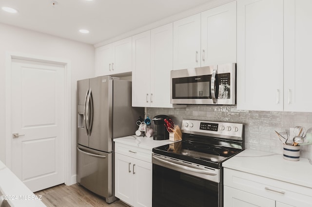 kitchen featuring white cabinets, light hardwood / wood-style floors, stainless steel appliances, and tasteful backsplash