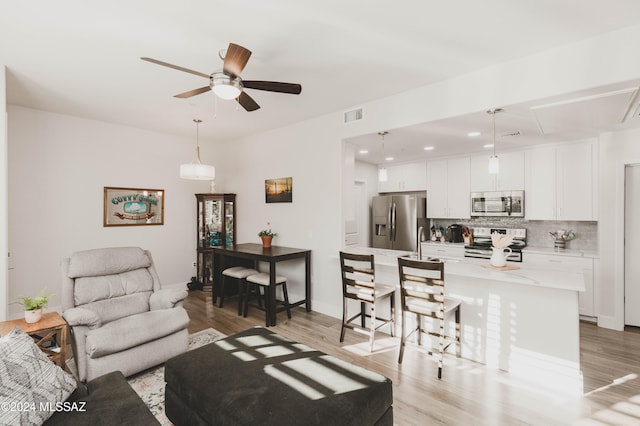 living room featuring ceiling fan, sink, and light hardwood / wood-style floors