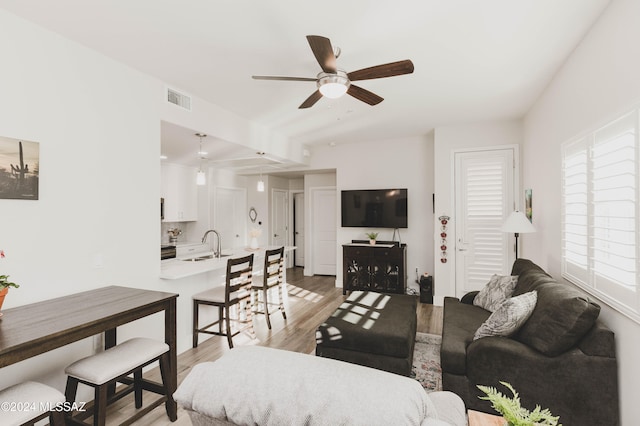 living room featuring ceiling fan, sink, and light hardwood / wood-style floors