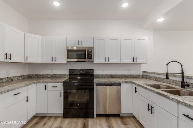 kitchen with sink, white cabinets, stainless steel appliances, and light hardwood / wood-style floors