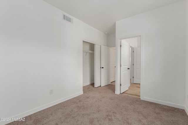 unfurnished bedroom featuring light carpet and a closet