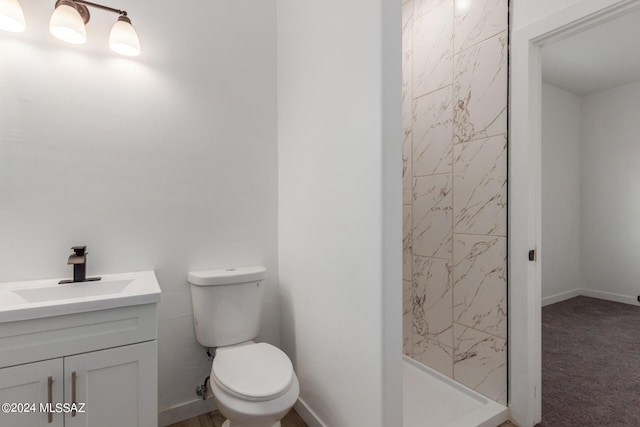 bathroom with vanity, toilet, and a tile shower