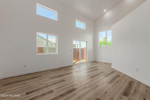 unfurnished living room with light hardwood / wood-style floors and high vaulted ceiling