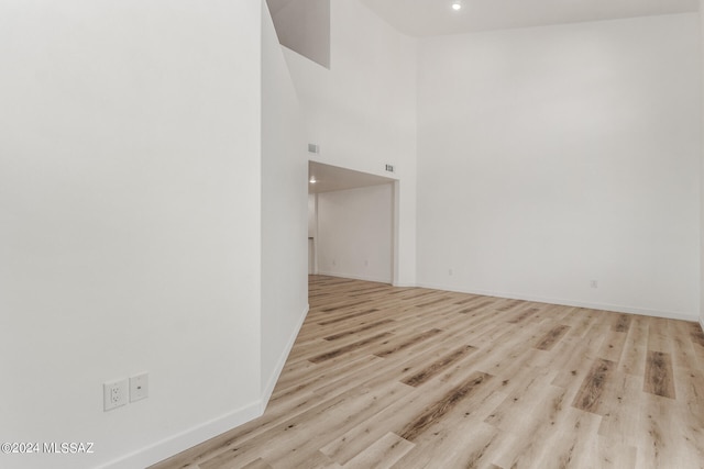 unfurnished room featuring light hardwood / wood-style flooring and a towering ceiling